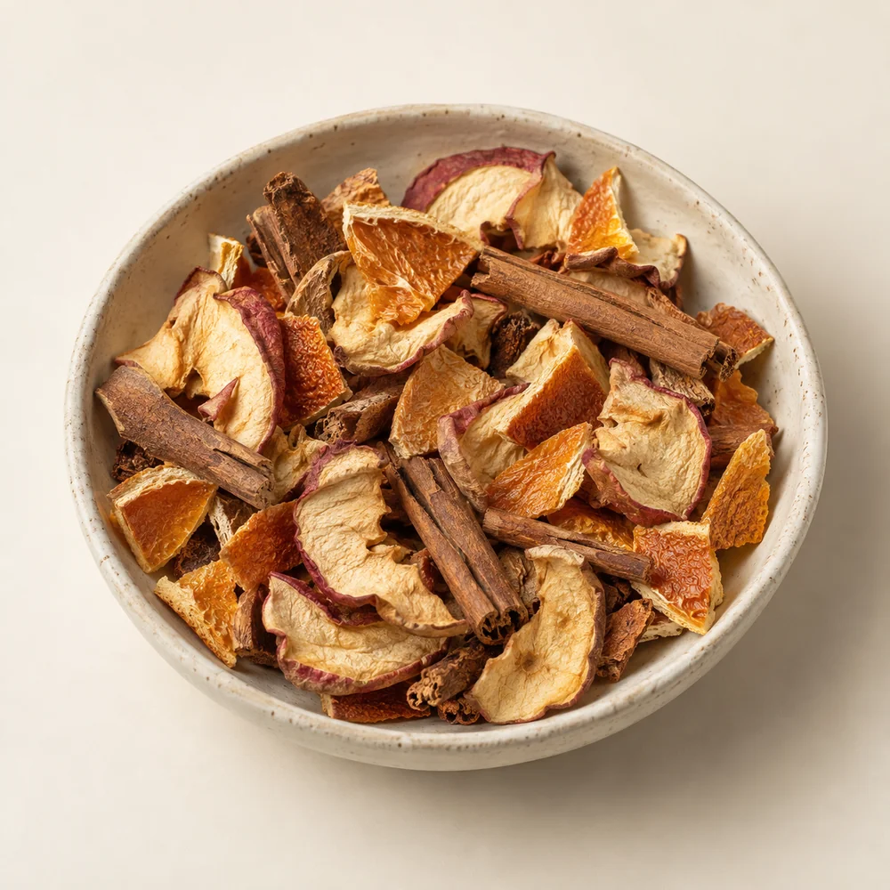 Mezcla seca de manzana, canela y naranja para infusión en plato marfil; imagen ilustrativa